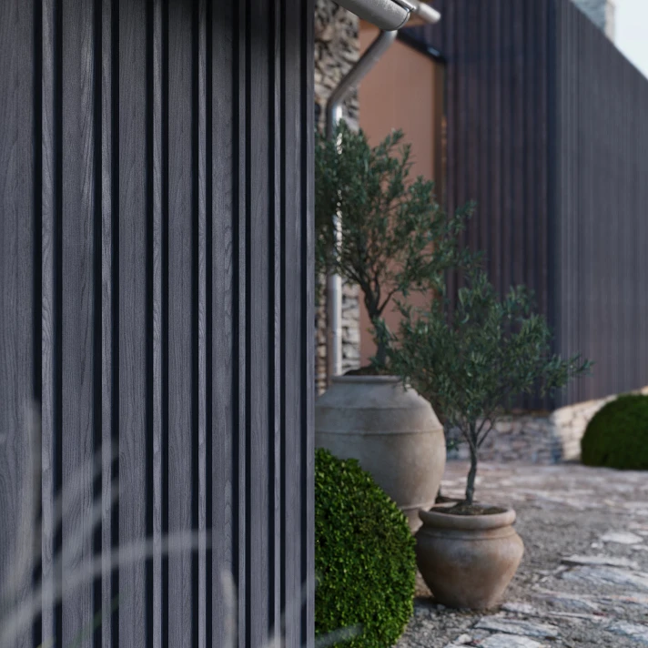 Bardage Millboard anthracite en pose verticale avec pots décoratifs, illustrant une façade moderne et durable dans un jardin méditerranéen.