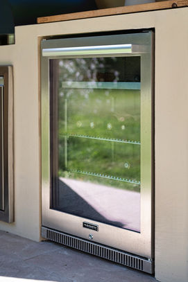 Détail du réfrigérateur vitré Dometic encastré dans le meuble en béton ciré — cuisine extérieure WAHO.