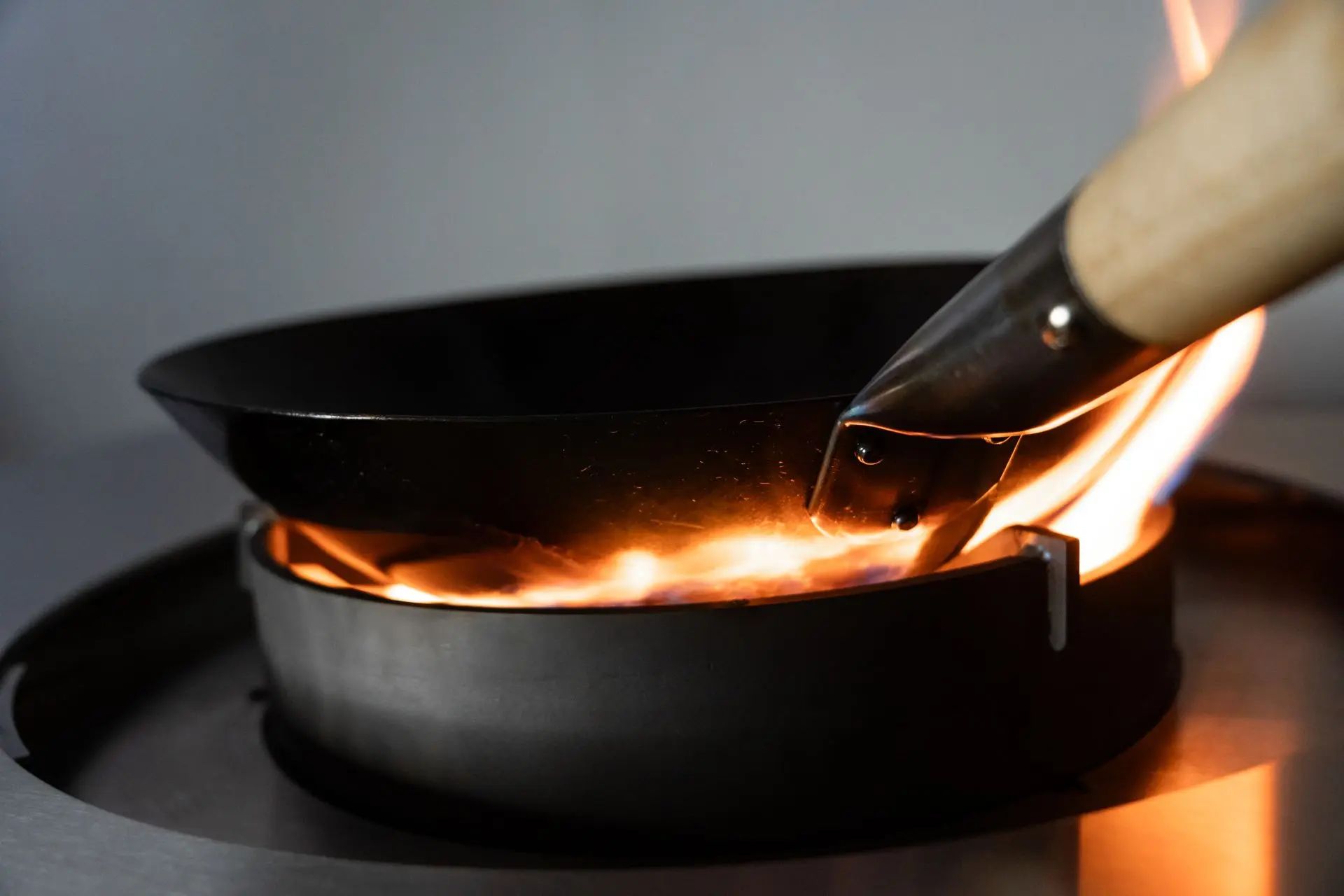 Gros plan sur un wok en pleine flamme sur le brûleur haute puissance du Flammkraft Block R, en situation de cuisson intense.