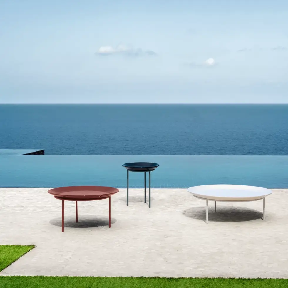 Tables basses BRISE 53, 54 et 56 alignées en extérieur face à la mer, dans trois coloris.