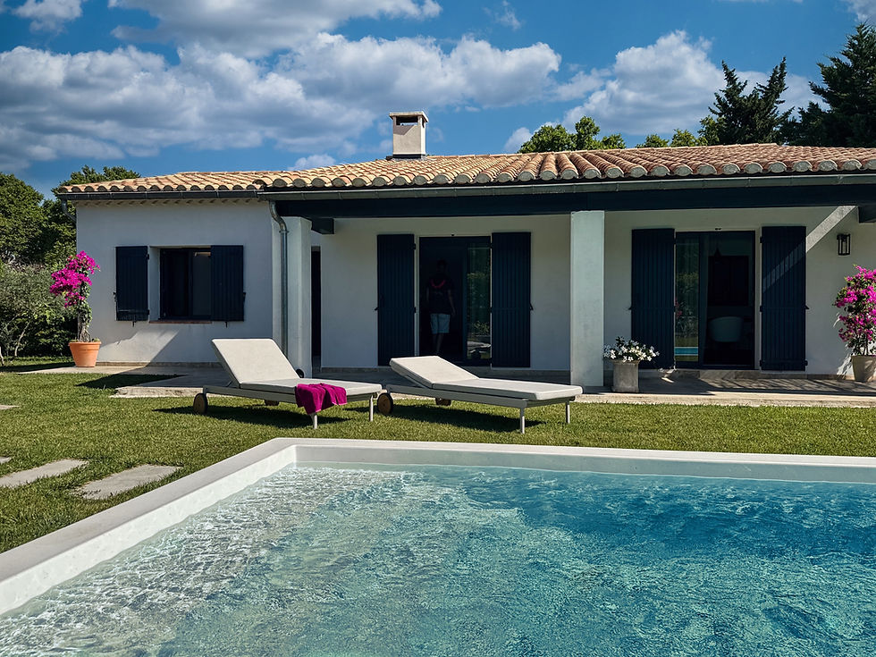 Façade de la maison provençale avec deux bains de soleil Skyline Tempo aluminium au bord de la piscine turquoise.
