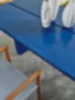 Détail du plateau bleu nuit de la table EIDOS en finition nuageuse, avec chaise en bois et assise textile rayée