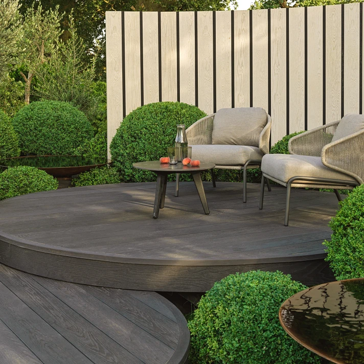 Espace lounge extérieur sur terrasse Millboard Weathered Oak avec panneaux de clôture décoratifs.