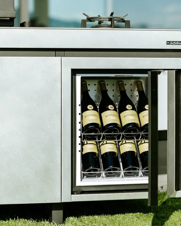 Gros plan sur la cave à vin intégrée dans la cuisine extérieure AGHER Fogher, avec bouteilles Bastianich parfaitement alignées et température contrôlée.
