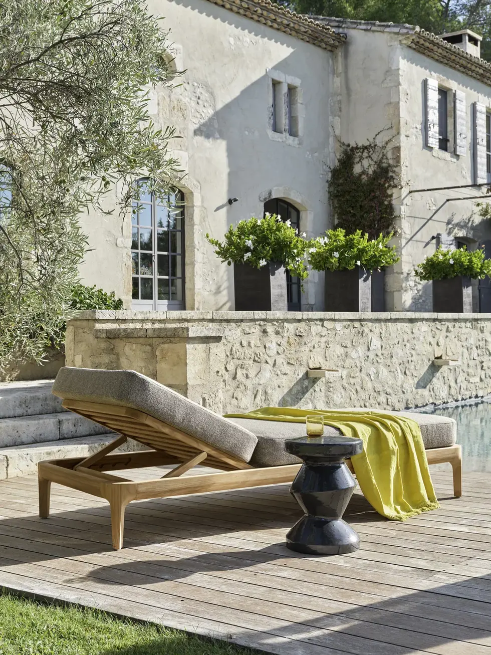 Bain de soleil Gervasoni MEDITERRANEO 81 en teck sur une terrasse en pierre avec coussin beige et serviette verte