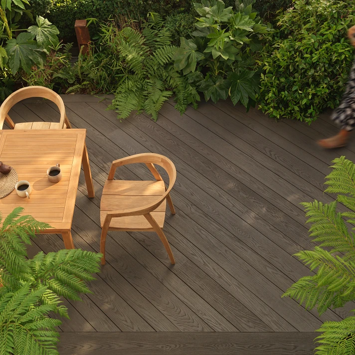 Terrasse Millboard Ebony Grey et salon de jardin naturel intégré dans un environnement végétalisé