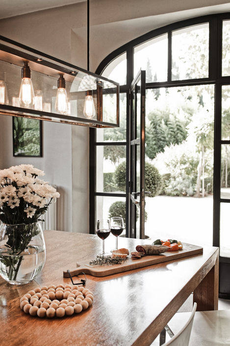 close-up of a wooden dining table adorned with a vase of white flowers and a serving board featuring charcuterie, cheese