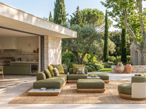 Aménagement extérieur haut de gamme avec salon de jardin design, cuisine extérieure intégrée et terrasse en pierre dans un jardin paysager méditerranéen lumineux.