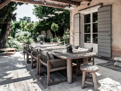 A beautiful wooden dining table set under a pergola, bathed in morning sunlight, surrounded by lush garden greenery, ideal for breakfast at sunrise
