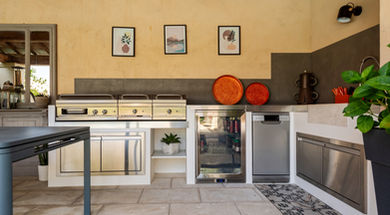 Façade complète de la cuisine outdoor : plancha, frigo 135 L, lave-vaisselle et rangements Napoléon sous décor mural graphique.