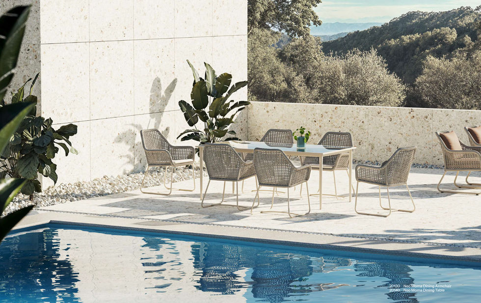 Ensemble repas extérieur NEO MOMA Skyline Design avec chaises tressées autour d’une table design au bord de la piscine