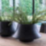 Vases Gommaire en fibre noire au design évasé, installés sous abri vitré, illustrant la protection idéale des vases décoratifs pendant l’hiver.