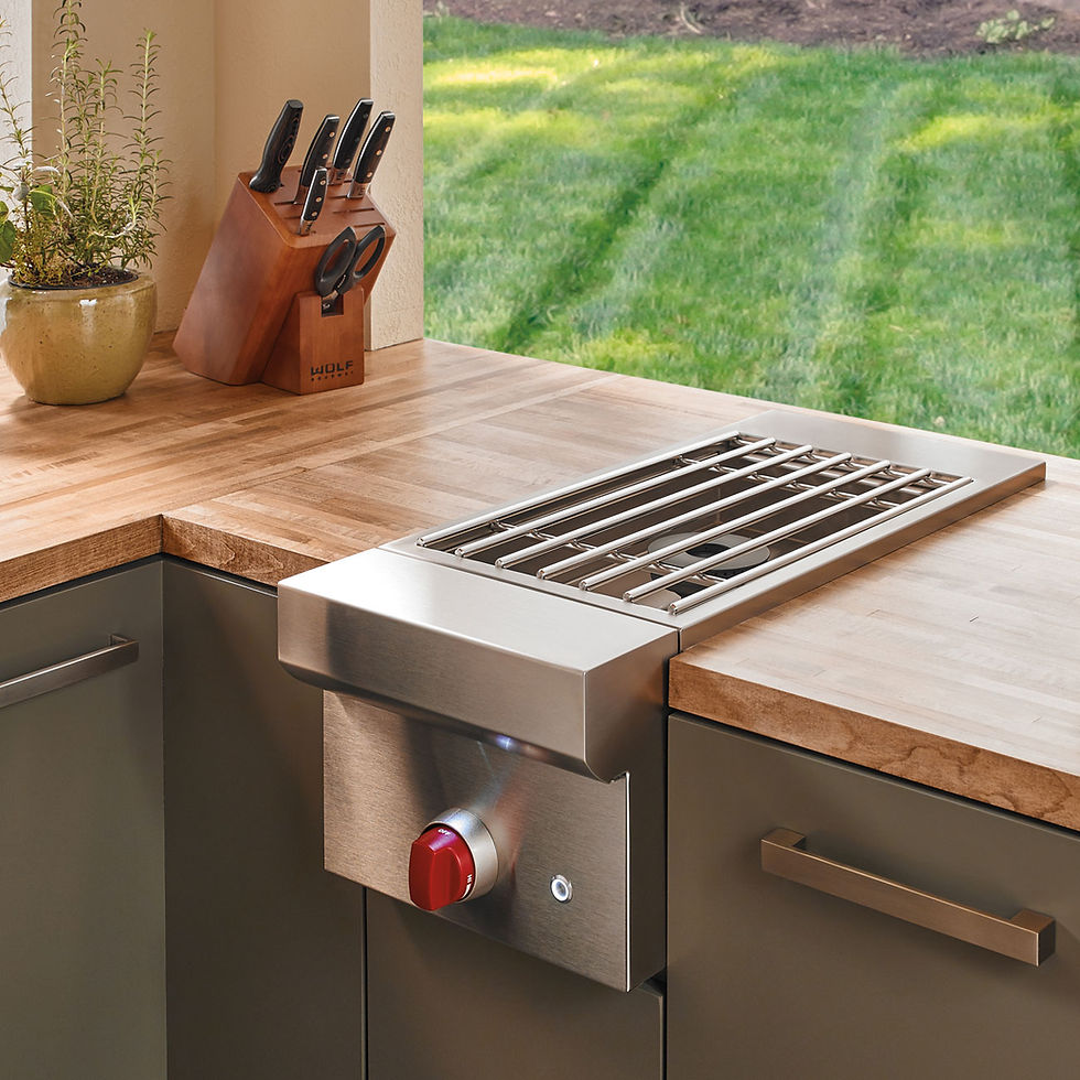Module de cuisson encastrable Wolf avec commande à molette rouge emblématique, intégré dans un plan de travail en bois naturel, illustrant une cuisine extérieure haut de gamme, élégante et personnalisable.