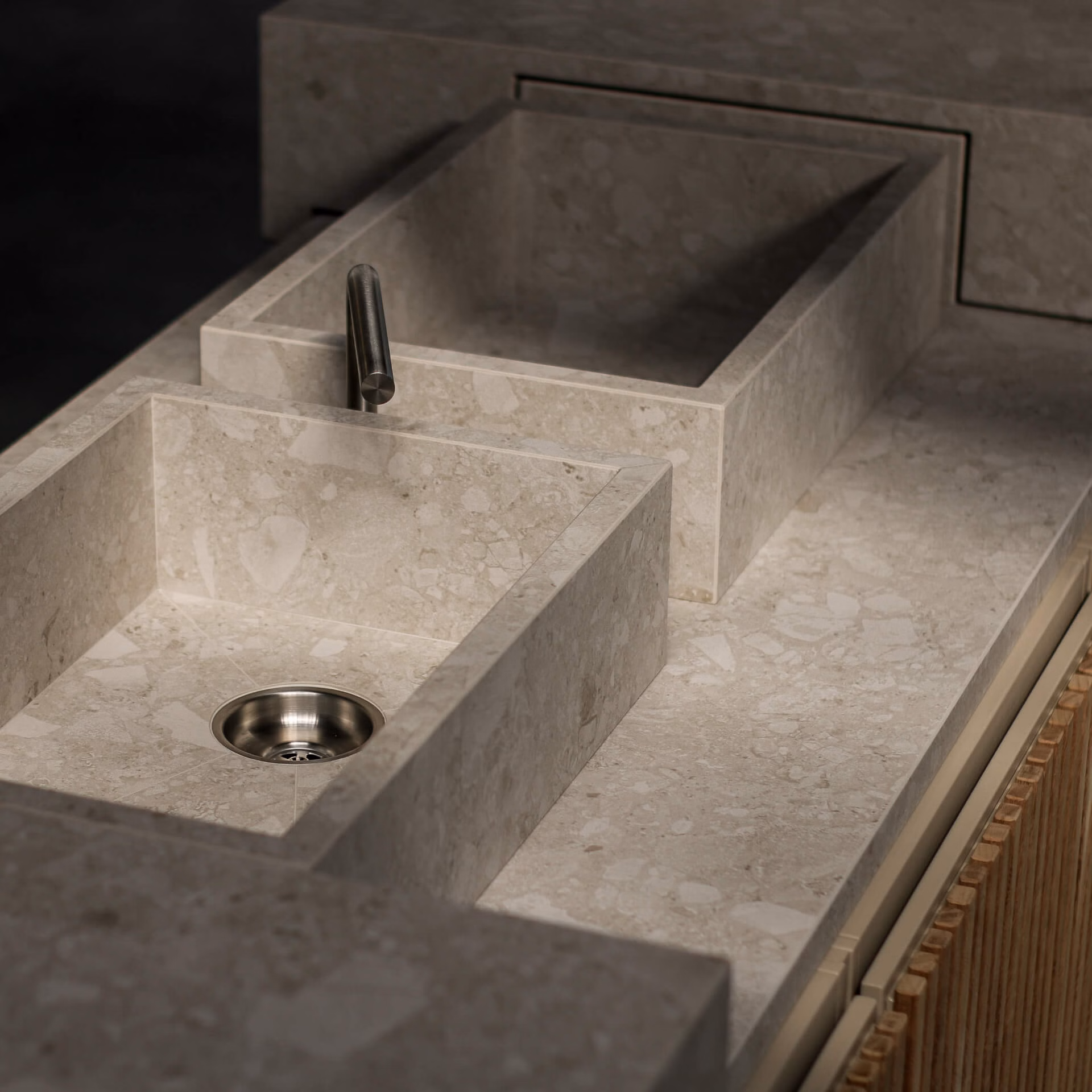Gros plan sur les deux éviers en pierre du Floating Bar, avec robinet minimaliste intégré dans un plan de travail céramique.