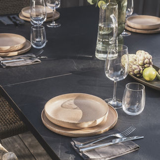 Table extérieure Cornilleau transformée en table de repas, dressée avec vaisselle élégante et décoration végétale, style naturel et raffiné.