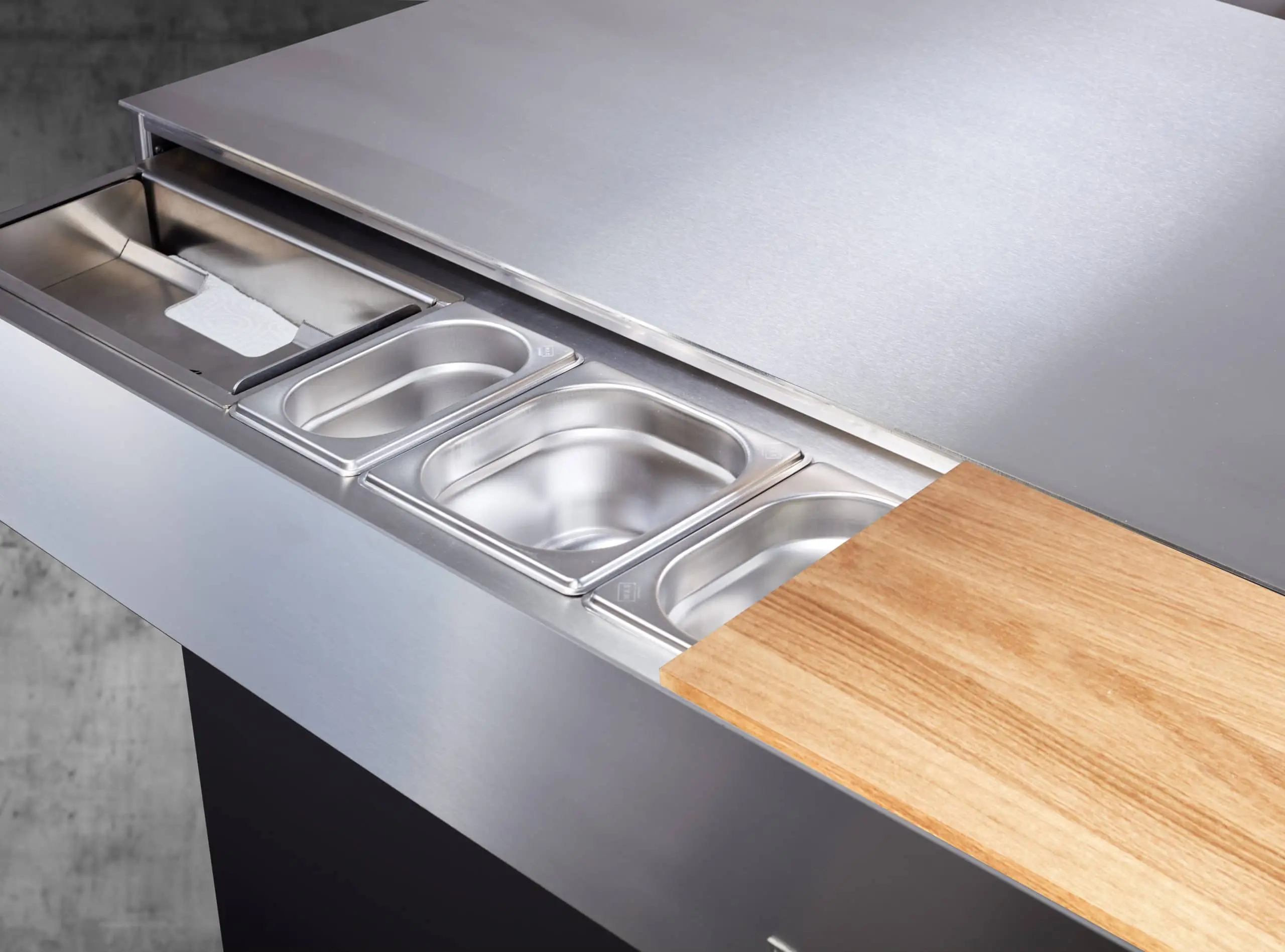 Tiroir coulissant du Block M Flammkraft avec bacs gastro intégrés en inox et planche à découper en bois pour un poste de préparation tout-en-un.