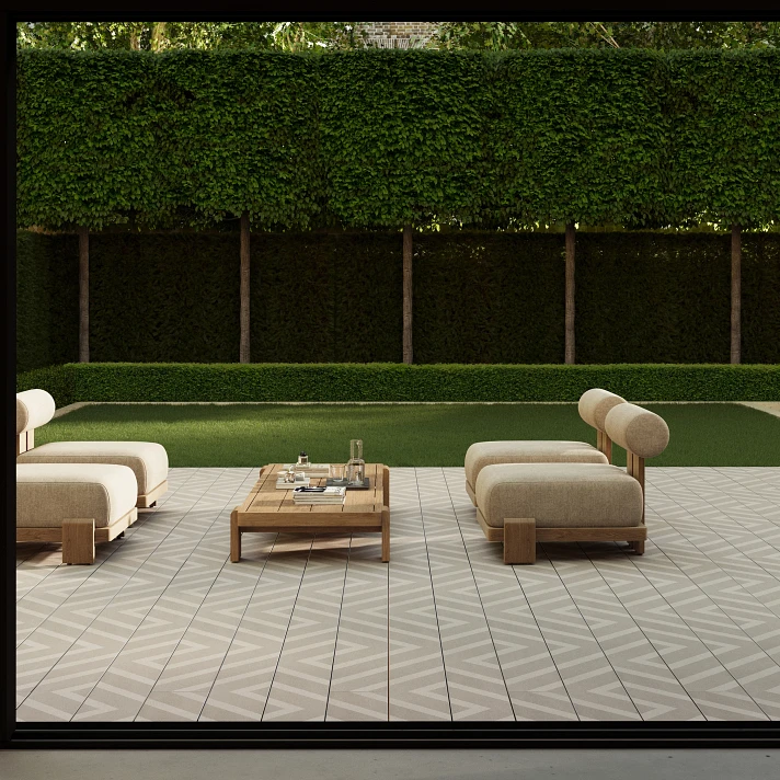 Terrasse contemporaine avec mobilier bas en bois clair, posée sur un sol en bois composite clair à motif graphique discret, vue sur jardin parfaitement taillé.