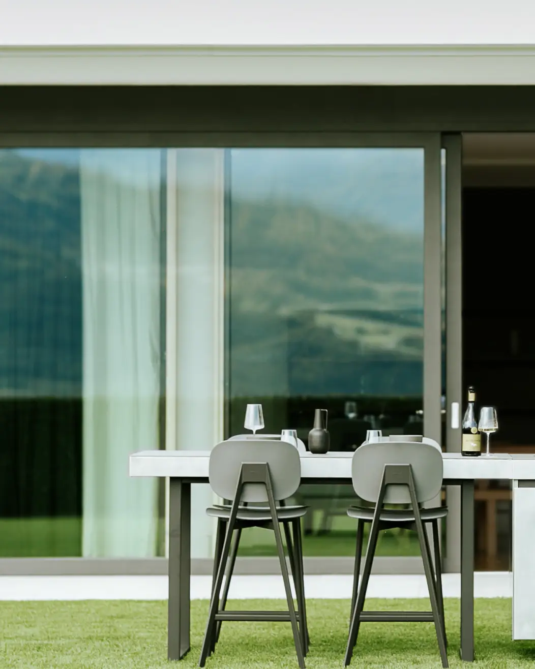 Table extérieure attenante à la cuisine AGHER, dressée pour un moment de partage, avec vue sur les montagnes et mobilier haut de gamme.