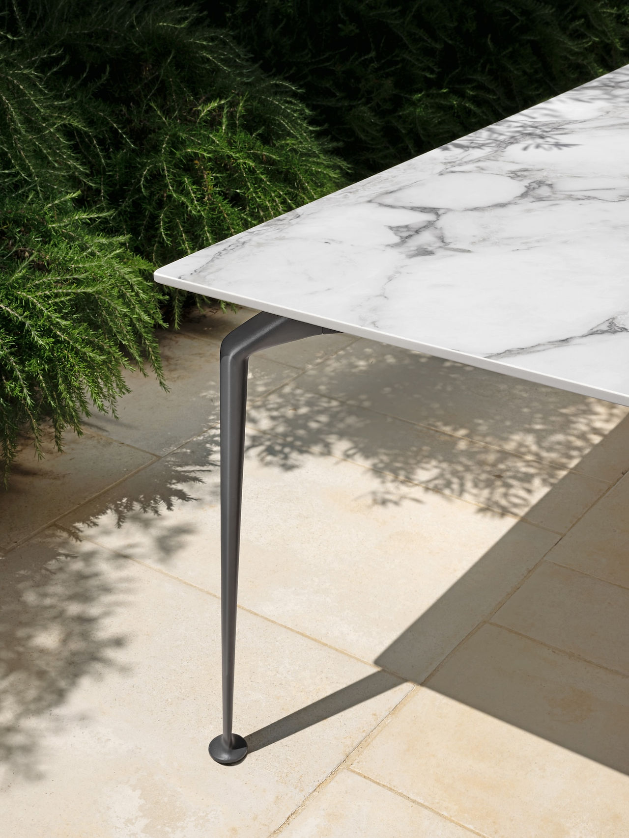 Détail d’une table de jardin haut de gamme avec plateau en marbre blanc et pieds en métal design, idéale pour un extérieur élégant et raffiné