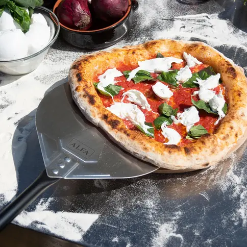 Pelle à pizza Alfa Forni avec une pizza garnie prête à enfourner