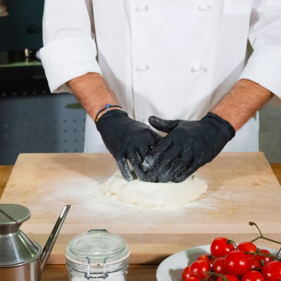 Chef pétrissant la pâte à pizza sur le plan de travail Alfa en bois