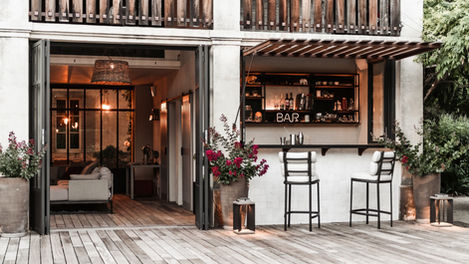 outdoor bar area at Mas de Campe, emphasizing the comfortable seating arrangement and inviting ambiance. The neon "BAR" sign adds a chic touch to the setup, making it an ideal place for evening gatherings