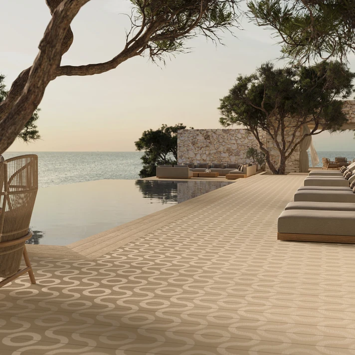 Terrasse détente avec chaises longues au bord d'une piscine à débordement, sol Millboard à motifs clairs.