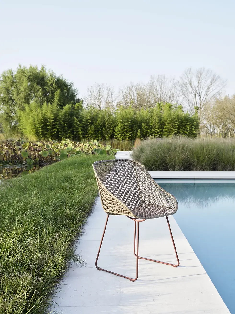 Chaise Colette 24 Gervasoni positionnée seule en bord de piscine avec verdure en arrière-plan