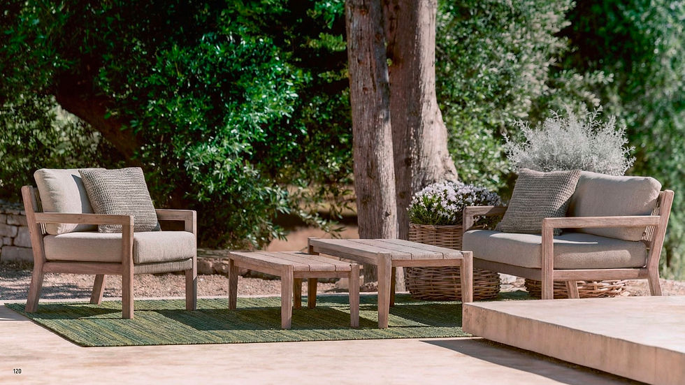 Salon de jardin en bois avec fauteuils et tables basses disposés sur un tapis outdoor vert, dans un espace ombragé entouré de végétation luxuriante.