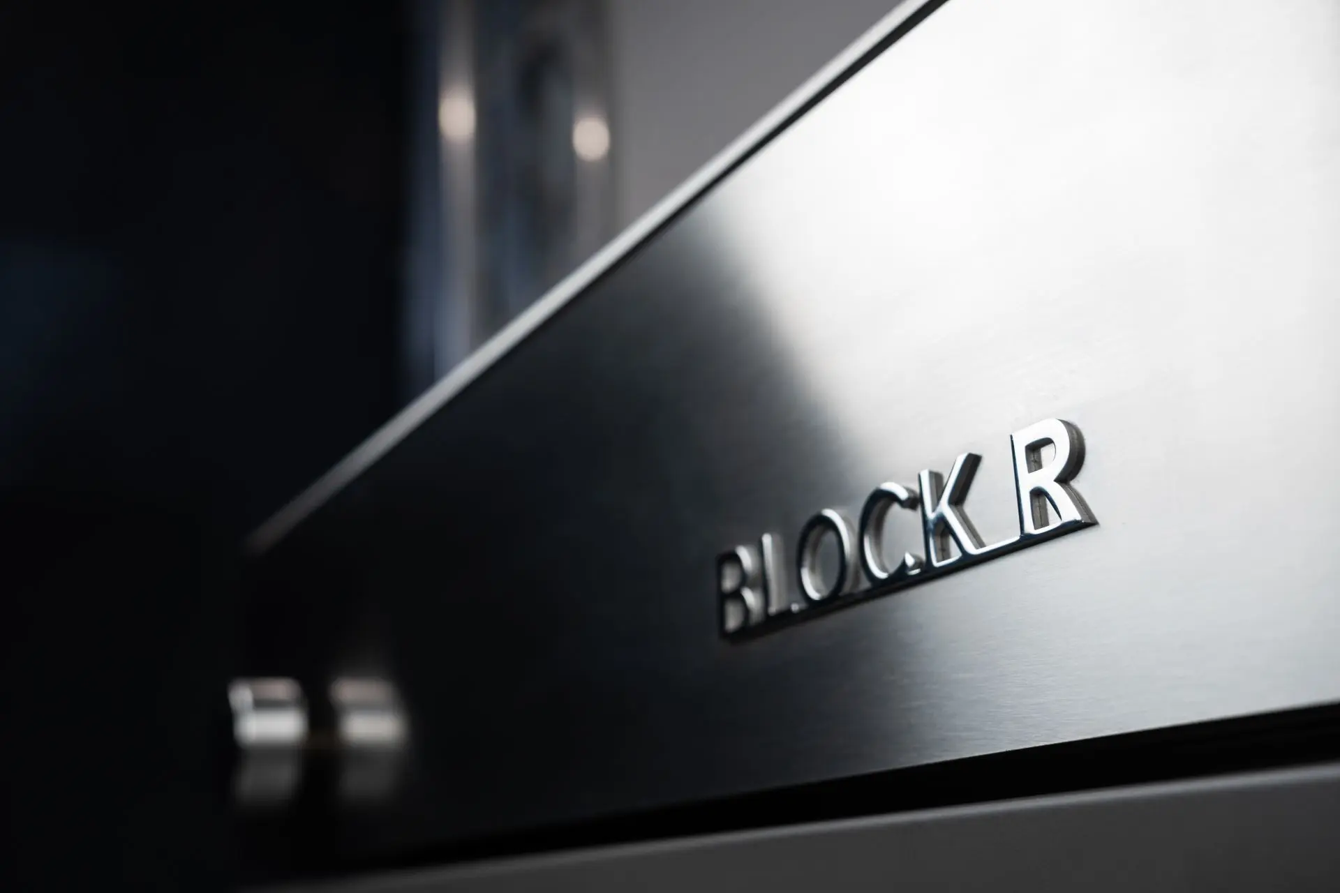 Zoom sur l’inscription métallique « BLOCK R » sur façade en acier inoxydable brossé, détail du design premium Flammkraft.