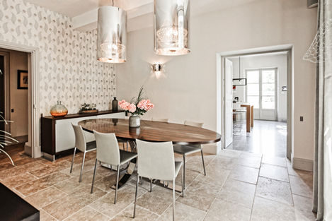 The dining room at Mas de Campe features a sleek wooden table surrounded by stylish chairs, beautifully illuminated