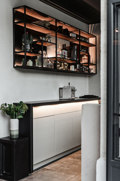 interior perspective of the pool house bar at Mas de Campe. The backlit shelves display various bottles and glassware, while the stylish cabinetry below provides ample storage, ensuring a seamless and luxurious bar experience for guests