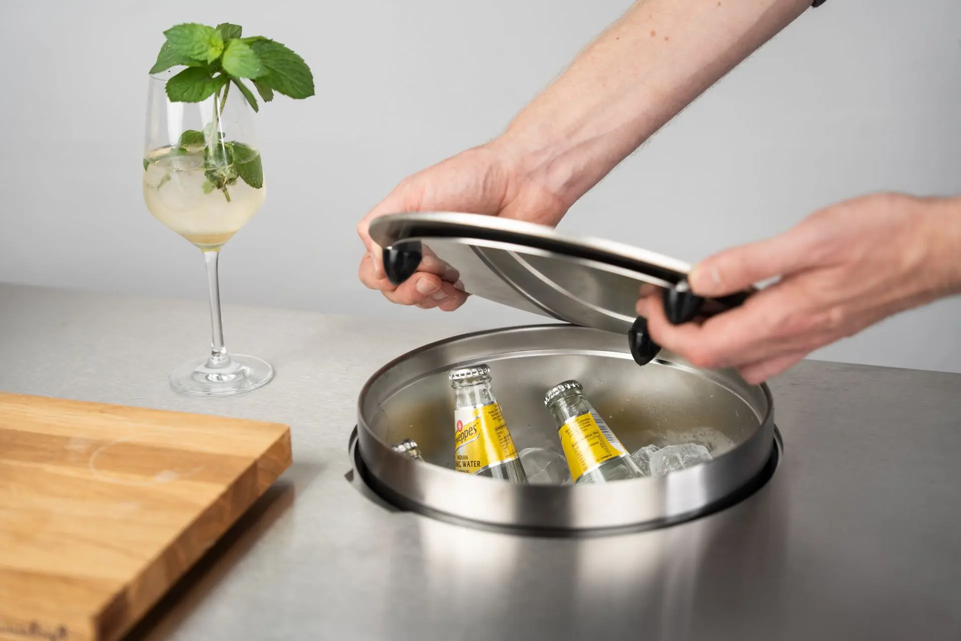 Bac à glaçons circulaire en inox du module bar Flammkraft, avec bouteilles rafraîchies, couvercle amovible et ambiance cocktail estivale.