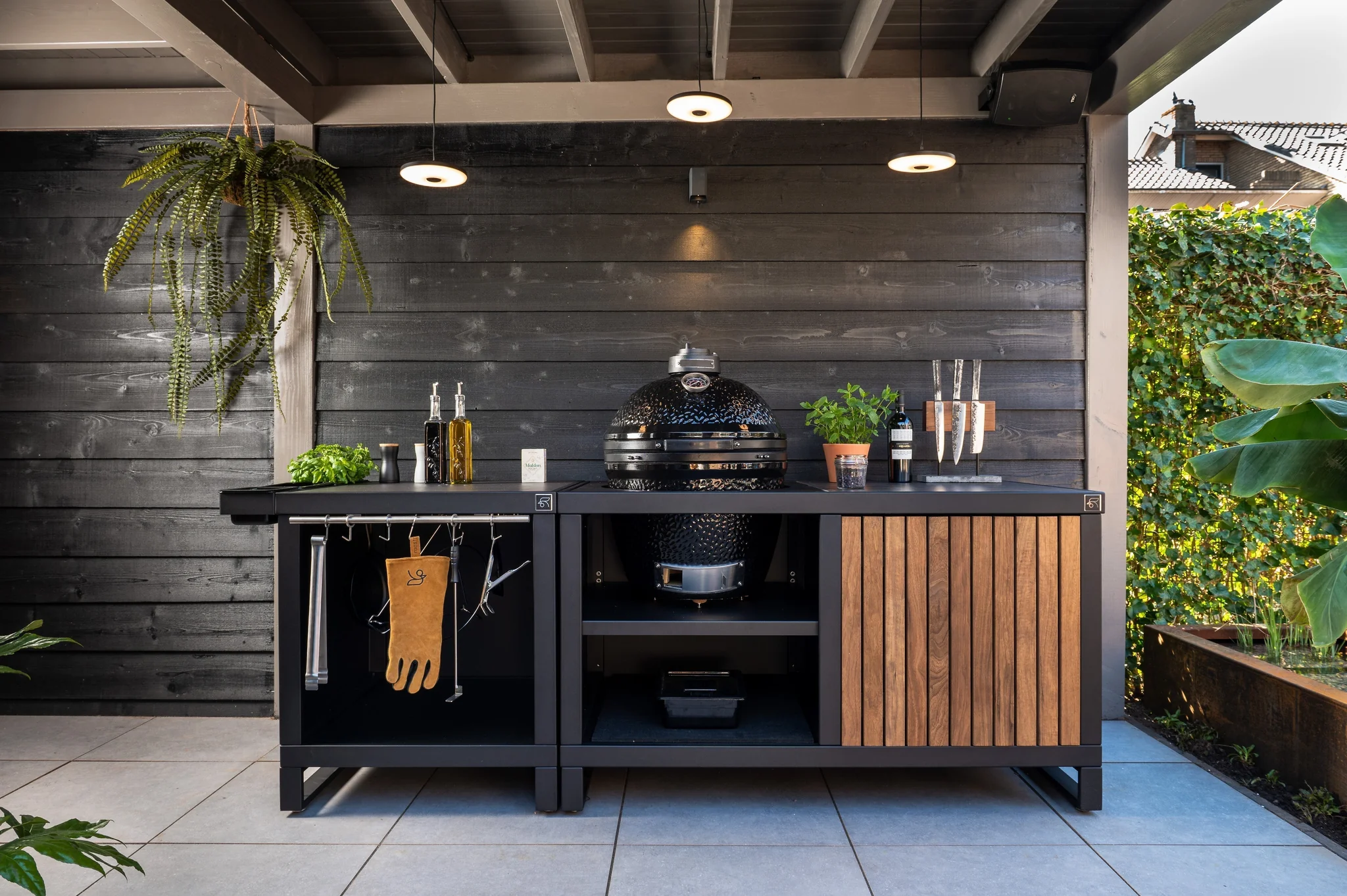Module RUBIX Roostr prêt pour Kamado avec rangements et crédence bois, plan de travail sombre, cuisine d’extérieur design installée par WAHO.
