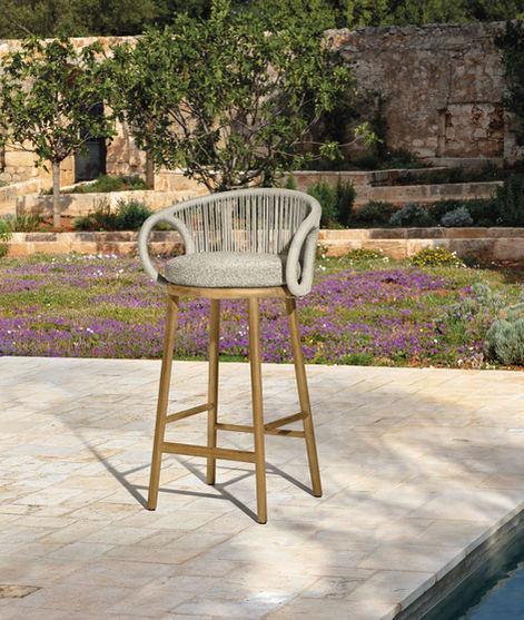 Tabouret haut KAREN de Talenti installé en bord de piscine, devant un jardin fleuri