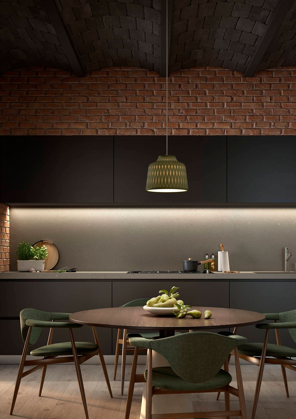 Suspension vert olive à abat-jour texturé au-dessus d’une table ronde en bois, dans une cuisine au mur de briques avec meubles sombres et éclairage linéaire sous les éléments.