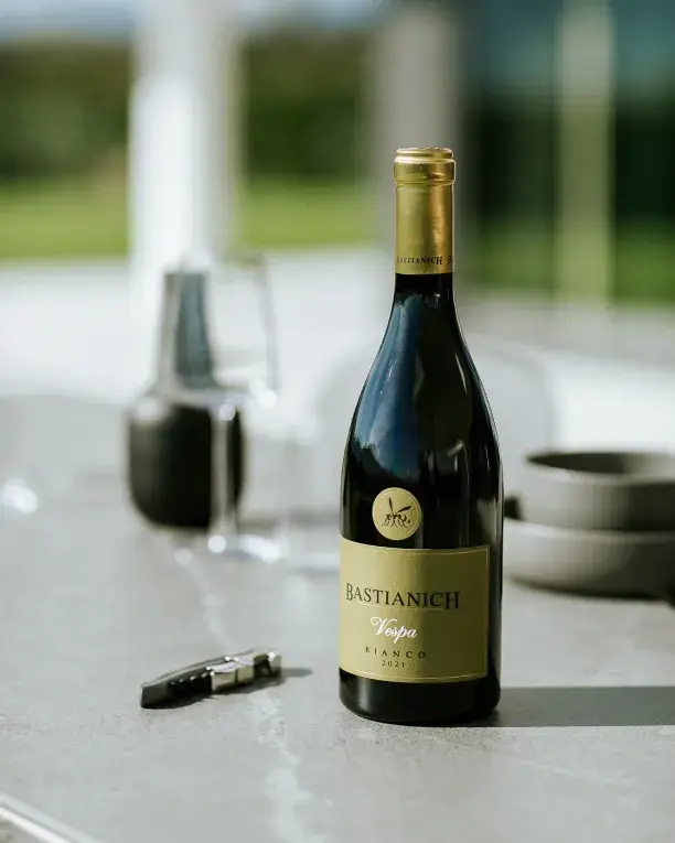 Bouteille de vin blanc Bastianich posée sur le plan de travail MDi Pacific Gris de la cuisine AGHER, avec tire-bouchon et verrerie raffinée.