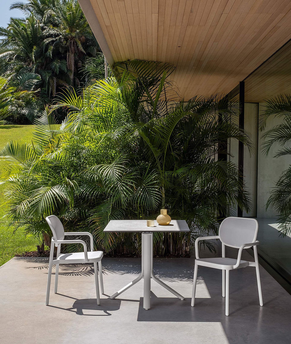 Chaises MEG Talenti blanches avec accoudoirs – sur terrasse en béton entourée de végétation