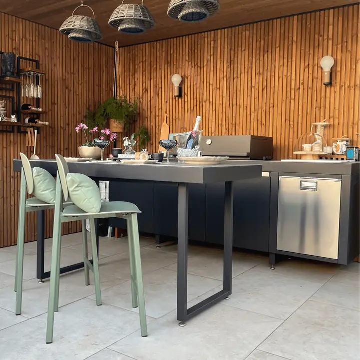 Cuisine extérieure modulable avec plancha, frigo et table snack, installée sous un abri en bois pour une expérience culinaire élégante et pratique en extérieur.