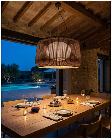 Suspension Bover FORA 90 marron grafito au-dessus d'une table dressée pour un dîner extérieur en soirée,