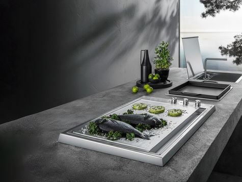 Cuisine extérieure avec teppanyaki inox et plancha encastrée, poissons et légumes en cuisson, vue mer.