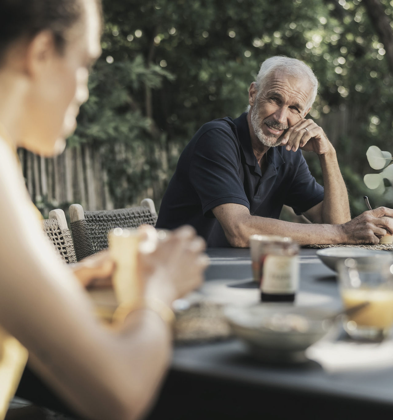 Homme assis à une table extérieure Cornilleau, profitant d’un moment convivial en plein air, ambiance détendue et naturelle.