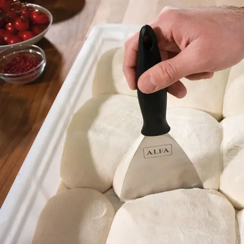 Spatule Alfa Forni décollant une boule de pâte dans un bac de fermentation