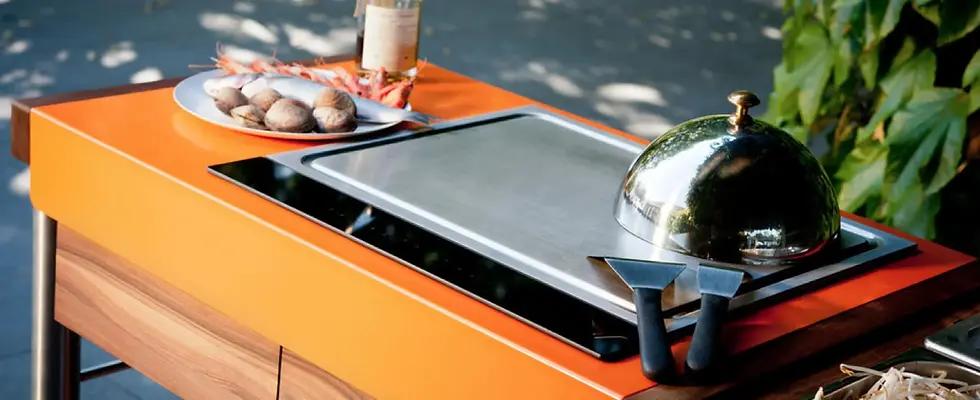 Teppanyaki inox encastré en cuisine extérieure, cloche et spatules de chef, poissons et crustacés prêts à snacker.