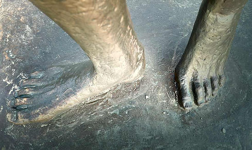 Dvi pėdos smėlyje, simbolizuojančios materialų žmogaus būties pagrindą ir skirtingų būties aspektų vientisumą.