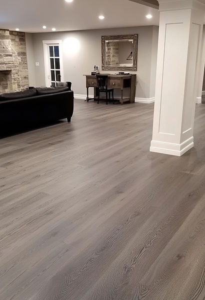 Residential living room with gray vinyl plank flooring, featuring a modern interior and professionally installed durable wood-look floors.