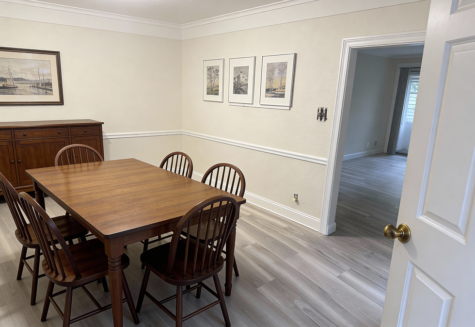 Dining room with a wooden table and six matching chairs on light gray wood-look vinyl flooring, connected to a hallway with similar flooring.