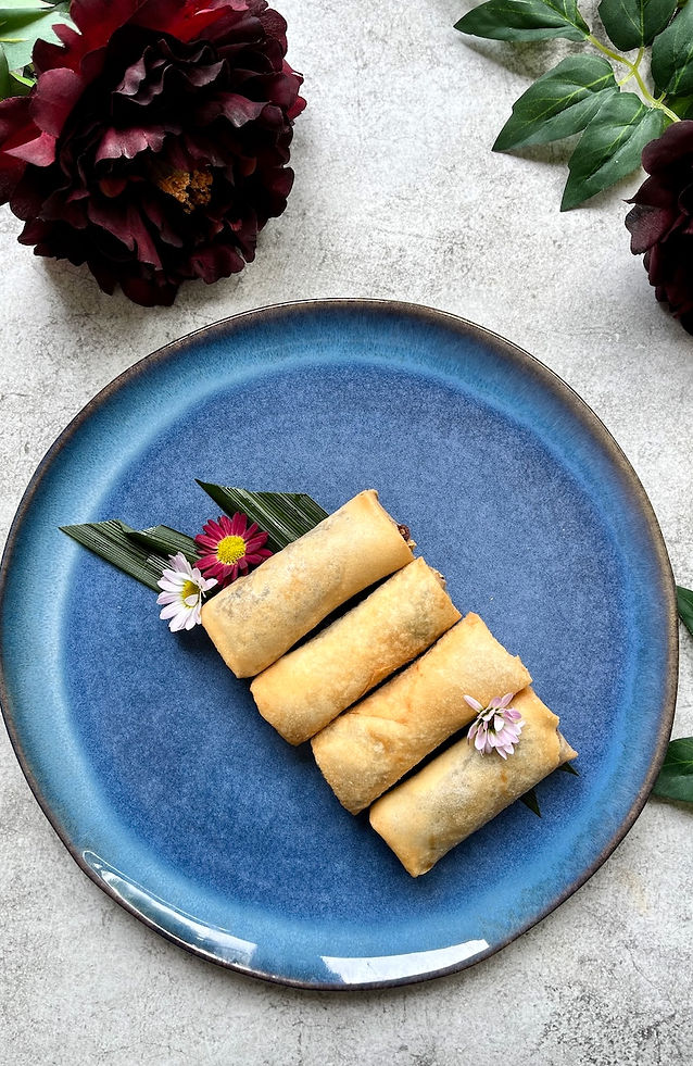 Crispy spring rolls on blue plate decorated with dark red flowers