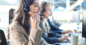 opératrice-du-service-client-avec-casque-souriant-avec-ses-collègues-en-arrière-plan.jpg