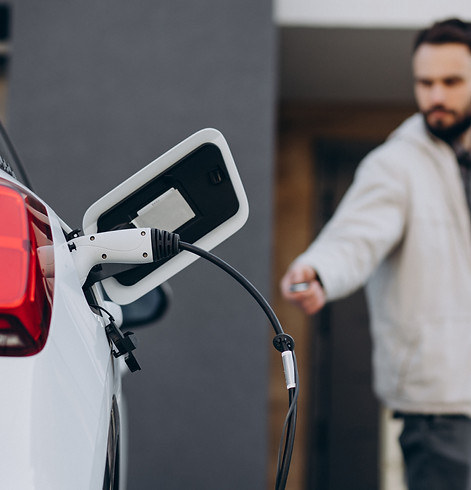 man-charging-electric-car-by-house.jpg